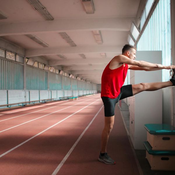 Runner stretching on a track, preparing mentally and physically.