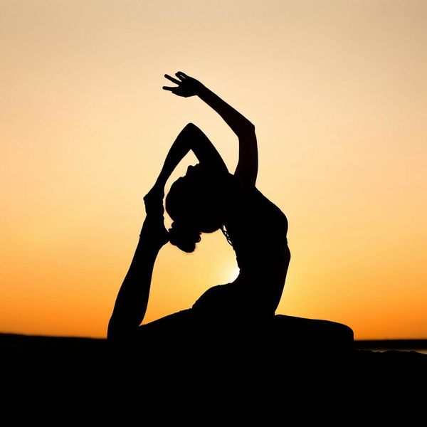 Silhouette of a person in a yoga pose against a sunset.